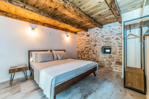 a bedroom with a bed and a stone wall at Luxury Villa Cortile in Benkovac