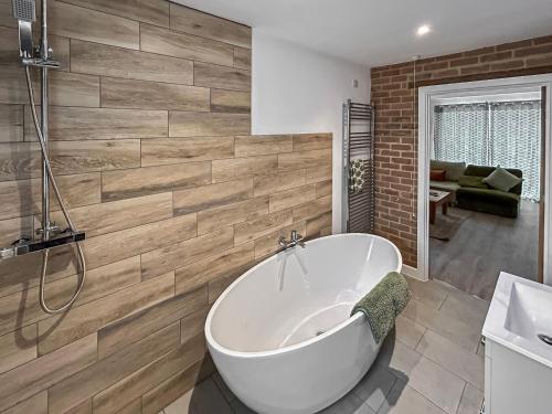 a bathroom with a white bath tub and wooden wall at No, 3 Rabbit Warren-uk44299 in Lenwade