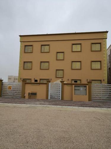 a large yellow building with a lot of windows at APARTMENTS HOQANI in Salalah