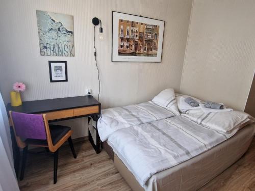 a small bedroom with a bed and a desk at Apartament Zielony in Gdańsk