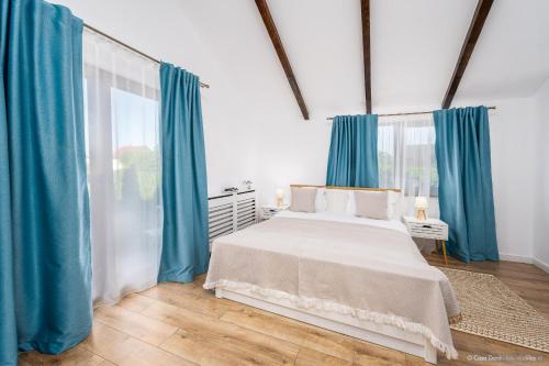 a bedroom with a large bed with blue curtains at Casa Dora in Suceava
