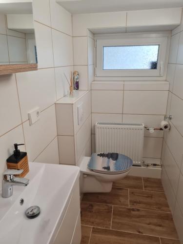 a bathroom with a toilet and a sink and a window at Hygge Apartment in Warstein