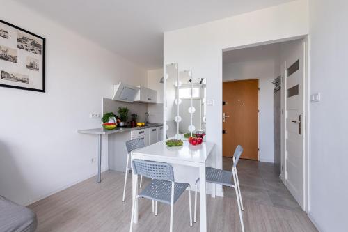 een keuken en eetkamer met een witte tafel en stoelen bij Przechodnia 2 - Good Apartments in Warschau