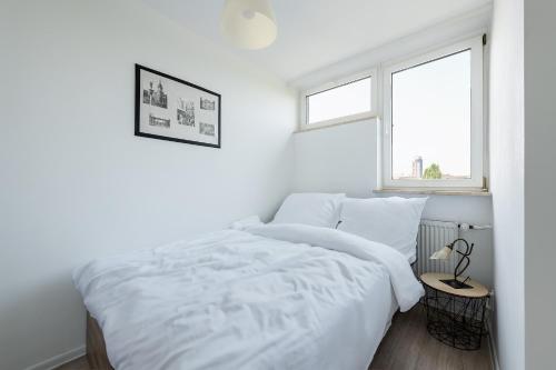 een witte slaapkamer met een bed en een raam bij Przechodnia 2 - Good Apartments in Warschau