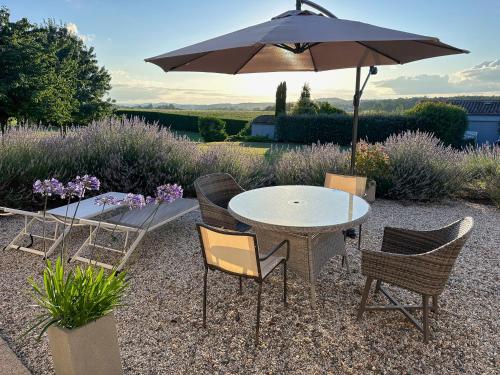 einen Tisch und Stühle mit Sonnenschirm in einem Garten in der Unterkunft Les Couroux in Saint-Julien-dʼEymet