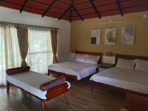 a bedroom with two beds and a chair and a window at Nature Valley Homestay Near Annapoorneshwari Temple in Kalasa