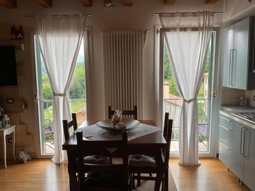 kuchnia ze stołem i krzesłami w pokoju z oknami w obiekcie Mountain Living Apartment Asiago w mieście Lusiana