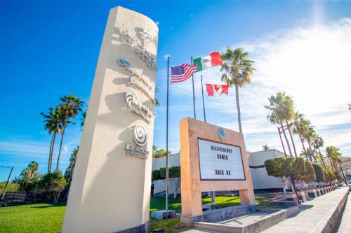 a surfboard in front of a sign and palm trees at Araiza Palmira Hotel y Centro de Convenciones in La Paz
