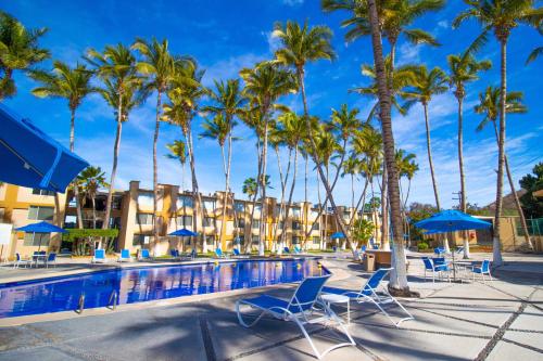 una piscina resort con palmeras y sillas azules en Araiza Palmira Hotel y Centro de Convenciones, en La Paz