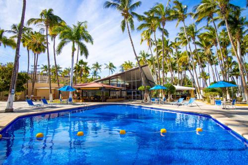 a swimming pool with palm trees and a building at Araiza Palmira Hotel y Centro de Convenciones in La Paz