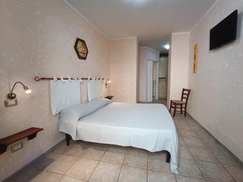 a bedroom with a white bed and a television at La Mezzanella Guesthouse in Porto Torres
