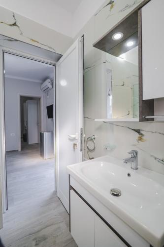 a white bathroom with a sink and a mirror at Luka Apartments in Sarandë