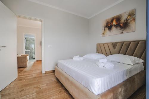 a bedroom with a large bed with white sheets at Luka Apartments in Sarandë
