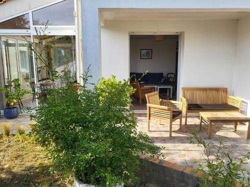 d'une terrasse avec 2 chaises et une table en bois. dans l'établissement Appartement 3 chambres 6 pers rez de Jardin 5min plage quartier du Phare Location du dimanche au dimanche en juillet et aout, à La Tranche-sur-Mer