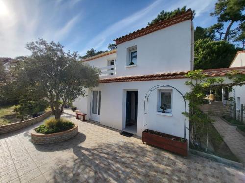 une maison blanche avec un arbre dans une cour dans l'établissement Appartement 3 chambres 6 pers rez de Jardin 5min plage quartier du Phare Location du dimanche au dimanche en juillet et aout, à La Tranche-sur-Mer