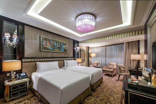 a bedroom with two beds and a living room at Narcissus Riyadh Hotel & Spa in Riyadh