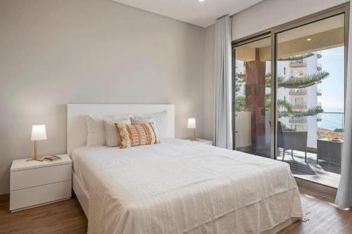 a white bedroom with a bed and a large window at Casa das Raposinhas I in Funchal