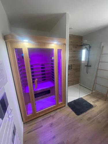 - une salle de bains avec des lumières violettes dans l'établissement Escapade Normande avec son sauna privé, à Le Tourneur