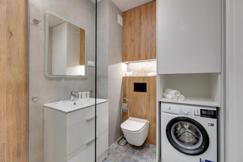 a bathroom with a washing machine and a washer at Apartament Letnica Białe Piaski by TriApart in Gdańsk