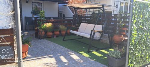 a porch with a bench and a bunch of plants at Zoe garden home in Spáta