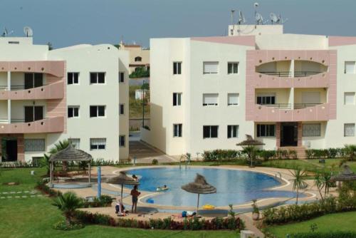 a resort with a large swimming pool in front of buildings at Les jardins de l'atlantique in Mohammedia