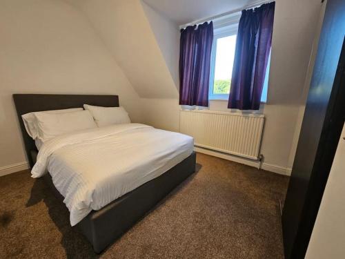 2 bedroom Flat in Camden في لندن: غرفة نوم بسرير كبير مع ستائر ارجوانية