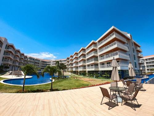 a large apartment building with a pool and tables and chairs at Solarium Residence no Porto das Dunas in Fortaleza