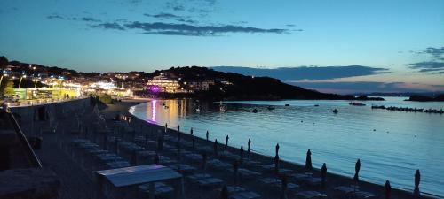 a beach with chairs and people in the water at night at Blue Bay Apartment in Cala Bitta