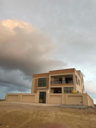 ein Gebäude mit einer Garage mit wolkigem Himmel in der Unterkunft شالية مارينا مرباط in Mirbāţ