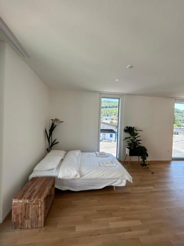 a white bedroom with a bed and a wooden table at The R Apartment Passwang, KLIMA, NEU, Balkon, Parking in Balsthal