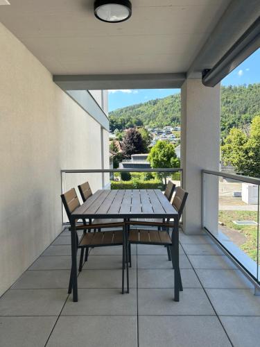 einen Holztisch und Stühle auf dem Balkon in der Unterkunft The R Apartment Passwang, KLIMA, NEU, Balkon, Parking in Balsthal