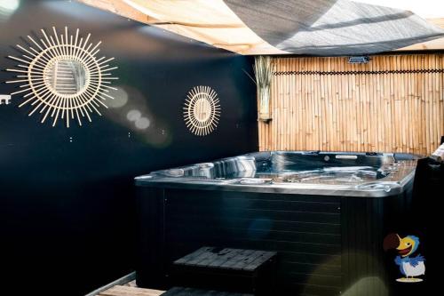 勒唐蓬的住宿－L'intemporelle - Piscine et Spa，一间带黑色墙壁的热水浴缸的浴室