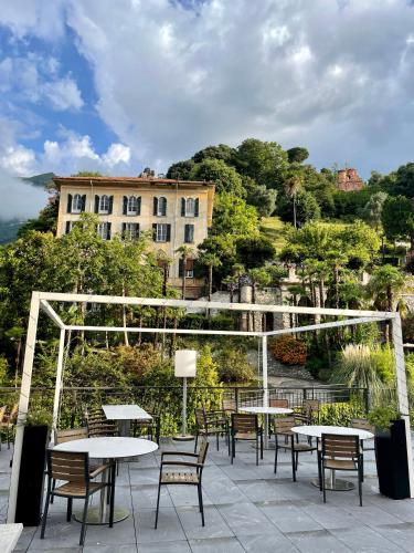 a patio with tables and chairs and a building at Hotel Bazzoni in Tremezzo