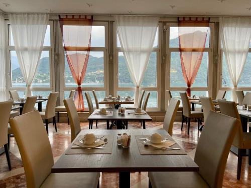 a restaurant with tables and chairs and large windows at Hotel Bazzoni in Tremezzo