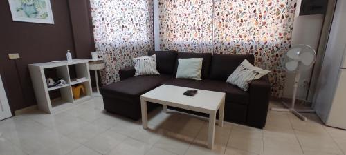 uma sala de estar com um sofá preto e uma mesa em Casa TINGUARO em Vecindario