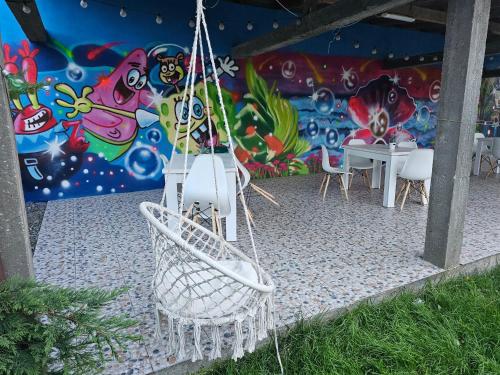 un tavolo e sedie di fronte a un murale di Casa Perla Mării a 2 Mai