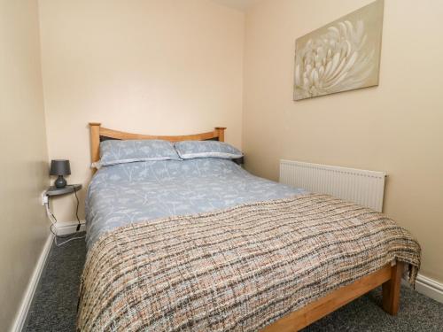 Un dormitorio con una cama con una manta. en Seashells en Hornsea
