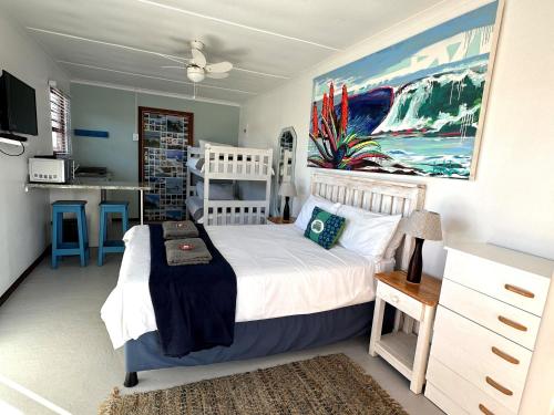a bedroom with a white bed and a painting on the wall at Happy Waves Holiday Home in Jeffreys Bay