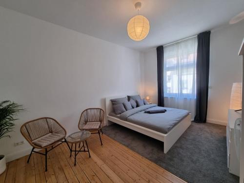 a bedroom with a bed and two chairs and a window at Süße Marie 3 in Karlsruhe