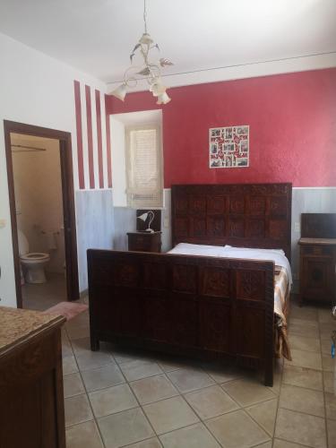 1 dormitorio con cama y pared roja en Casa Raffaello en Castiglione dʼOrcia