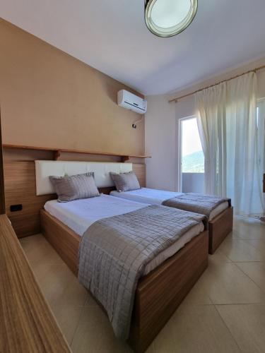two beds in a bedroom with a large window at Rozmarine in Pëllumbas