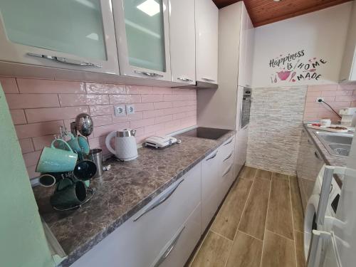a kitchen with pink walls and white cabinets at Stella's Garden in Paleo Tsifliki