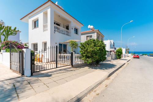 a white house with a fence on a street at Lemon Tree Villa in Paralimni