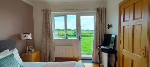 a bedroom with a bed and a window and a television at Golf'Inn Enniscrone in Enniscrone