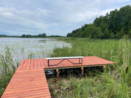 a wooden dock with a bench on the side of a lake at Dwa Żurawie - Głuszyn in Głuszyn