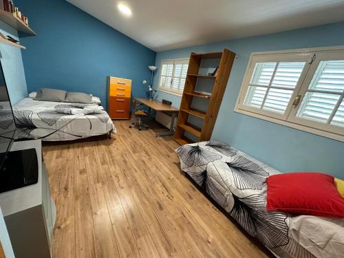 Vallirana的住宿－Casa con piscina y vistas en Vallirana/Barcelona，配有蓝色墙壁和木地板的客房中的两张床