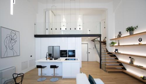 a kitchen with white walls and a staircase with stools at Loft Milano Manifatture2 in Milan