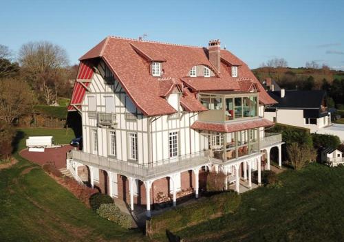 une grande maison blanche avec un toit rouge sur une colline dans l'établissement La Plage en Normandie, à Pourville-sur-Mer