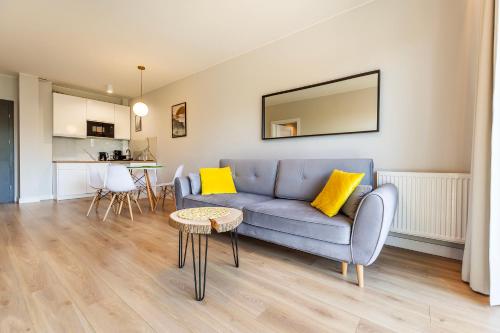 a living room with a blue couch and yellow pillows at VacationClub – Sosnowa 4 Apartament 40 in Mielno