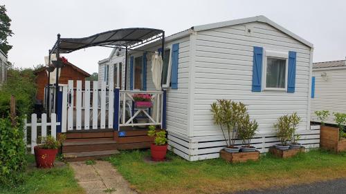 a small white house with a fence and plants at Sylvie propriétaire du mobil-home in Saint-Pair-sur-Mer